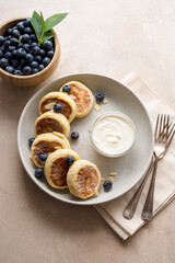 Cottage cheese fritters, ricotta pancakes with sour creamand bleberries. Healthy food. Warm background