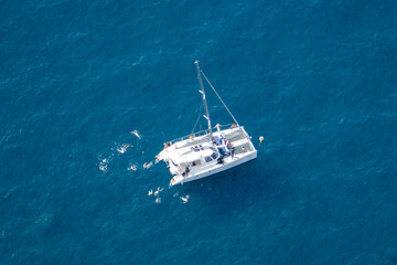 Boat and people swimming in the highest sea cliff in Europe at 1,903 feet (580 meters) above the sea. Cabo Girão bay, Madeira Island, Portugal.