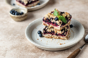 Homemade blueberry crumble bars on a plate decorated with mint on beige. Healthy breakfast...