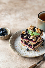 Homemade blueberry crumble bars on a plate decorated with mint and tea cup. Healthy food concept. Text space