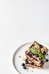 Homemade blueberry crumble bars on a plate with mint on white textured background. Healthy snack...