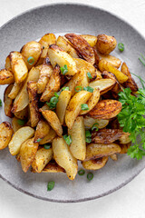 Roasted new potatoes, baked baby potatoes in a plate with herbs. Gray background.