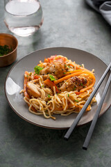 Homemade noodles with chicken meat and vegetable, dark background. Asian style food.