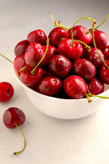 Fresh red cherries in white bowl, on dark background. Summer delicious fruit.