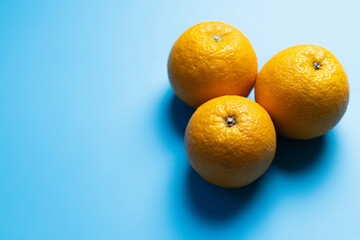 Top view of oranges on blue background with shadow.