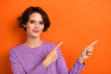 Photo of shiny pretty girl dressed purple pullover pointing empty space isolated orange color background