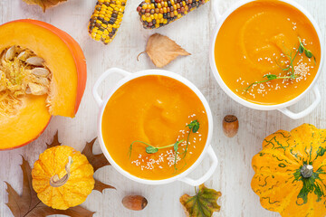 Pumpkin cream soup on white wooden background. Directly above, close up