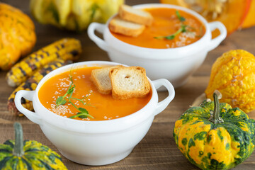 Pumpkin cream soup with croutons on wooden background.