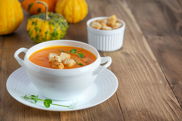 Pumpkin soup with croutons on wooden background. Copy space