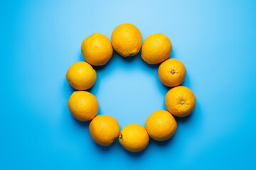 Flat lay with frame from oranges on blue background.