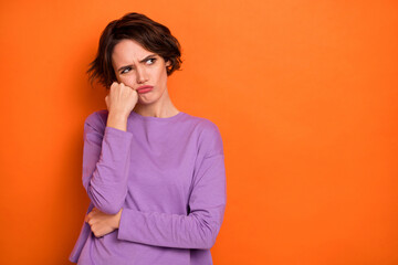 Photo of unsatisfied moody person hand touch cheek look empty space isolated on orange color background