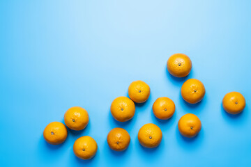Top view of bright tangerines on blue background.