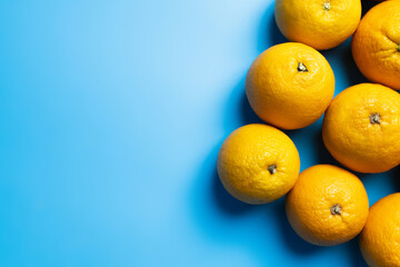 Top view of natural oranges on blue surface.