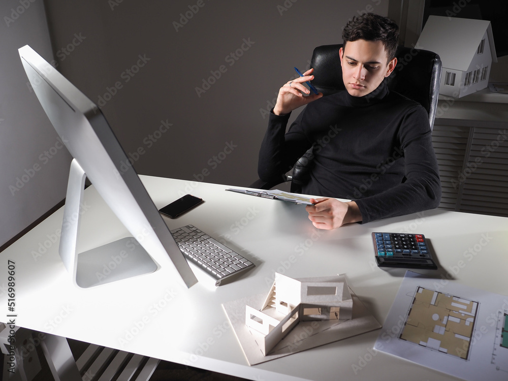 Poster male designer is working on an architectural project. engineer at his desk with drawings and layout 