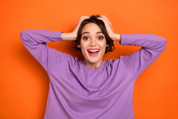 Photo of funny excited girl dressed purple pullover arms head smiling isolated orange color background