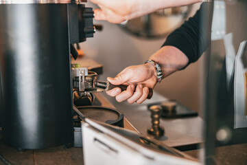 Barista grinds coffee beans pouring into a portafilter using coffee machine