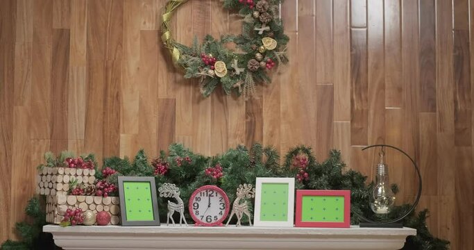 Pink shiny clocks, silver christmas deer toys and photo frame mockups in front of christmas tree branches