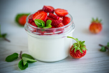 Sweet homemade yogurt with fresh ripe strawberries in a glass jar