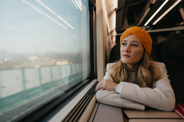 houghtful Woman Traveling by Train – Solo Passenger Gazing Out Window with Scenic View and...