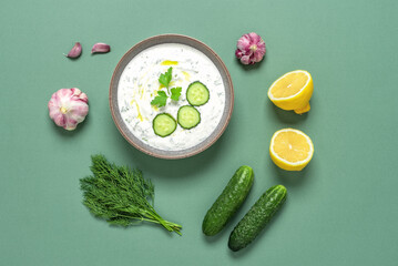 Obraz na płótnie Canvas Tzatziki sauce. Greek sauce made from yogurt and vegetables. Green pastel background. Top view, flat lay.