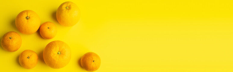 Top view of ripe mandarins and oranges on yellow background, banner.