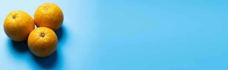 Top view of oranges on blue surface with shadow, banner.