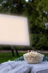 Vertical view of isolated popcorn bowl and a projector screen in the background playing a movie in...
