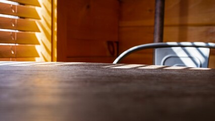 A wooden table in a wooden room and a chair with the sun drifting inside the room