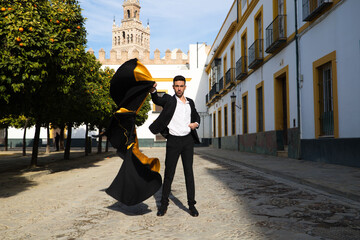 Portrait of young and handsome gipsy man, dressed in black and red shoes dancing with a black and...