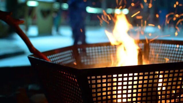 Backdrop, a defocused image of a bright flame, a night street fire with sparks in an iron grate, a grill