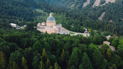 Fototapeta premium Aerial view of The Sanctuary of Oropa, Roman Catholic building in the Biellese Alps, Northern Italy. Tourist attraction and famous place of pilgrimage in Piedmont. Drone photography.
