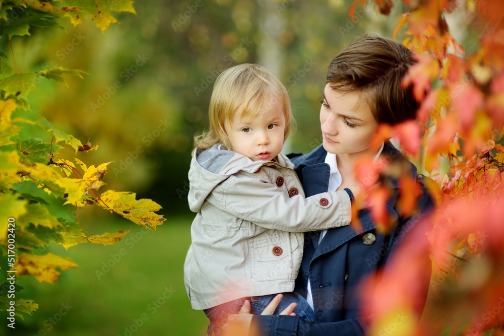 Wall mural Cute teenage sister cuddling with her little brother. Adorable teenage girl holding toddler boy. Children with large age gap.