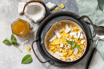 Vegan healthy breakfast. Cereal granola breakfast flakes with coconut non-dairy alternative milk and fresh coconut slices on a stone tabletop. View from above.