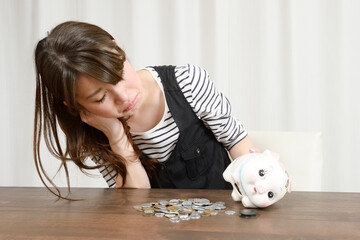 貯金箱を開けて悲しむ女性