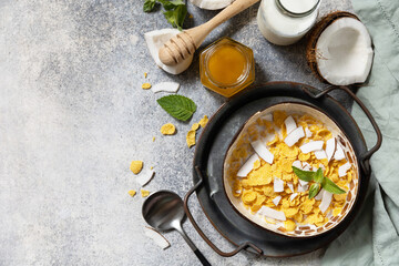 Vegan healthy breakfast. Cereal granola breakfast flakes with coconut non-dairy alternative milk and fresh coconut slices on a stone tabletop. View from above. Copy space.