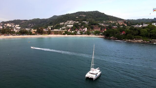Aerial Flying Over White Yacht With Parasailer Going Past At Over Kata Beach In Phuket. Dolly Forward