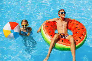 boy and a girl swim in the outdoor pool. Summer holidays with children. Swimming aids and...