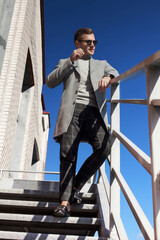 A man in a coat descends the stairs against the blue sky, fashion.