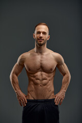 Fototapeta na wymiar Young muscular caucasian man looking at camera and showing his naked torso while posing shirtless isolated over grey background. Sports, workout, bodybuilding concept