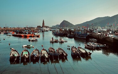 Fishing boats in the harbor against the hills and blue sky. Dalian, China. - obrazy, fototapety, plakaty