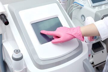 Doctor cosmetologist adjusts the device for photorejuvenation using the touchscreen