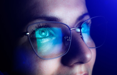 Girl works on internet. Reflection at the glasses from laptop..Close up of woman's eyes with black...