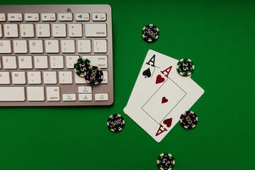 Top view of keyboard, cards with aces and playing chips on a green table, casino, black jack, poker concept