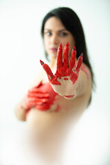 young woman with red painted hand, raised as a stop sign, concept of sexual abuse, violence, blood, harm to women. Gender violence. Latina woman