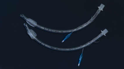 two endotracheal tubes lie on a dark background close-up. medical instruments, instruments for intubation and anesthesia - obrazy, fototapety, plakaty