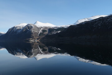 Fototapeta na wymiar Mountains and forests reflecting in fjord in Norway