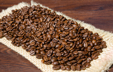 Roasted coffee beans close-up on burlap.