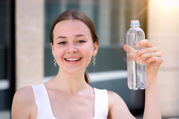 Portrait of beautiful teenager pretty girl, young happy thirsty woman is drinking pure fresh water...