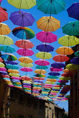 Fototapeta na wymiar Colourful umbrellas hanging over a picturesque street in the city