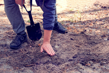 Man digs soil with a shovel in the forest. Black shovel in human hands.